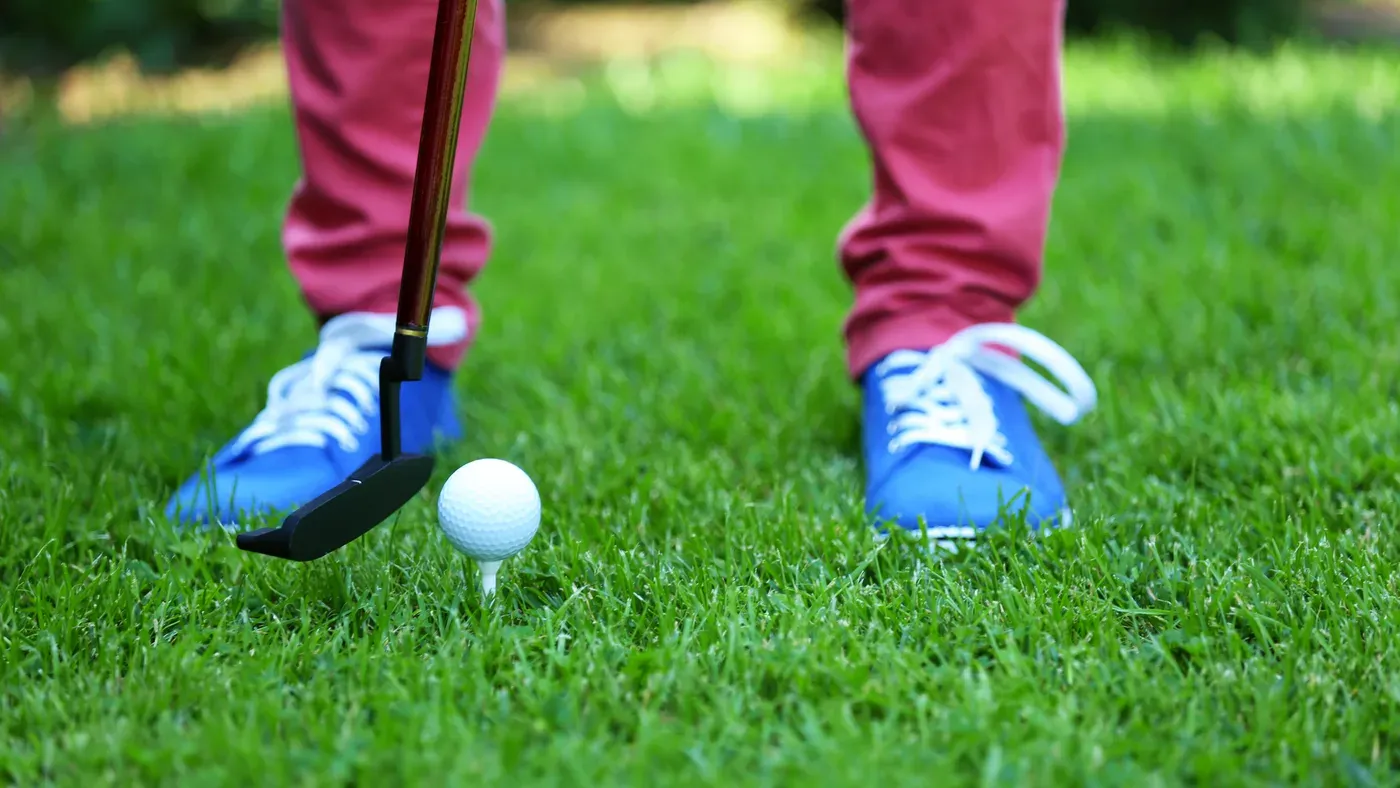 Litet barns hand håller upp en golfboll
